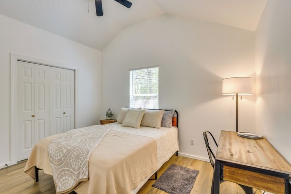 A bedroom with a bed, a nightstand, a lamp, a window, and a door. - Boating & Fishing Home Base Near the Sabine River! (Joaquin)