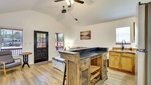 A kitchen with a wooden island, a ceiling fan, and a view of the outside. - 3 Mi to Sabine River: East Texas Cabin Hideaway (Joaquin)