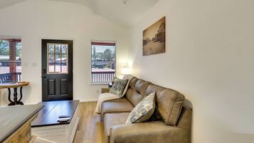 A living room with a brown leather sofa, a small table, a door, and windows with blinds.