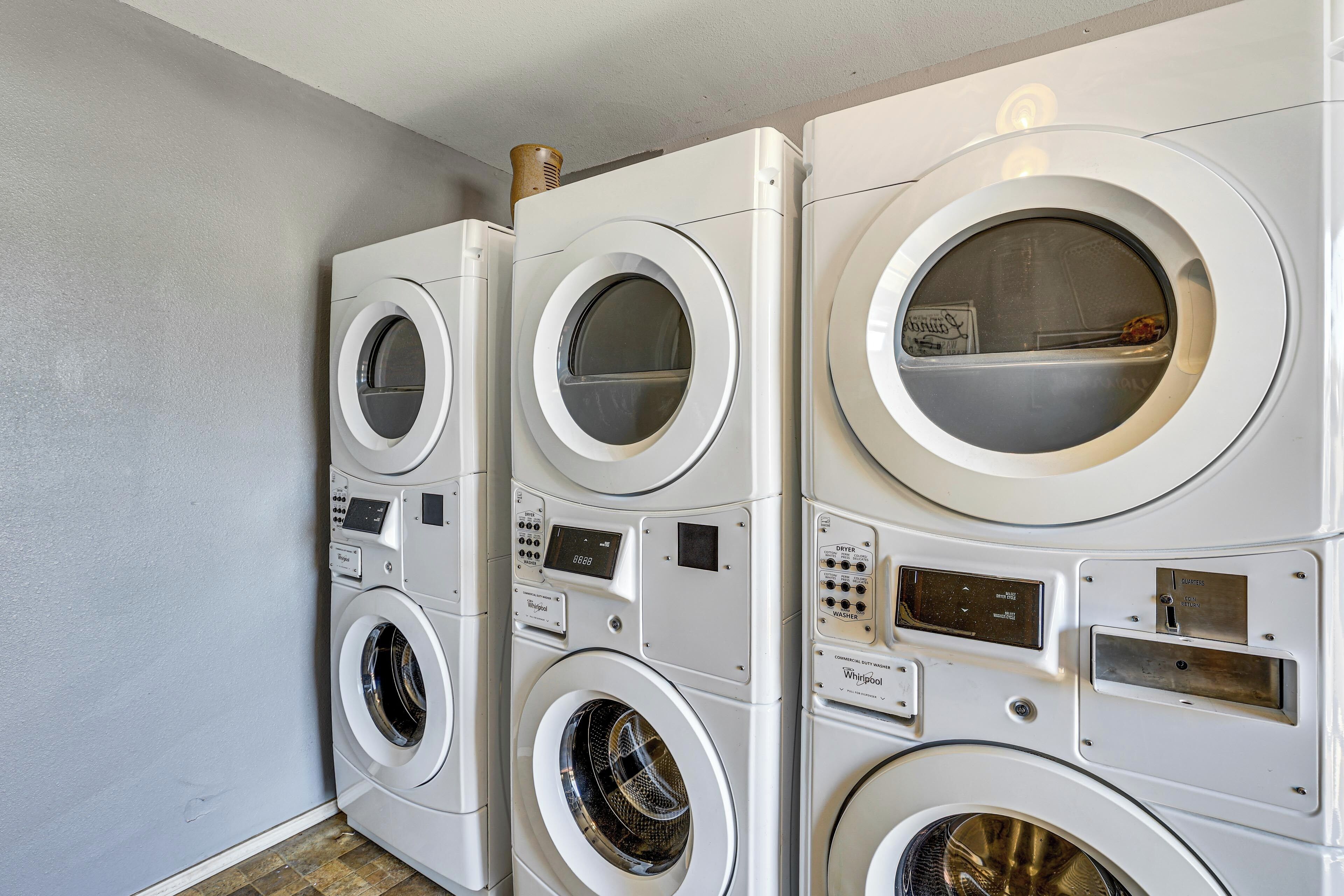 A row of stacked front-loading washing machines in a laundry room.
