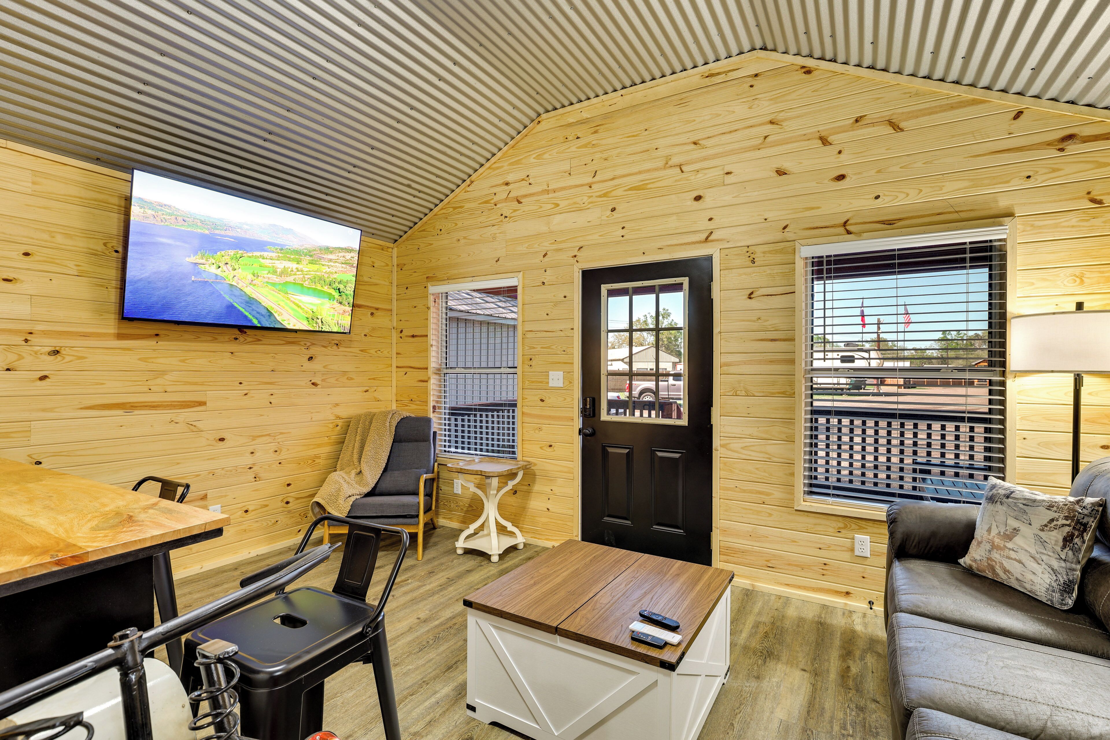 A cozy cabin interior with a television, a couch, a table, and a door.