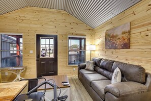 A cozy cabin interior with a wooden ceiling, a leather couch, a painting, and a table with a lamp. - Modern Sabine River Cabin, 3 Mi to Boat Launch! (Joaquin)