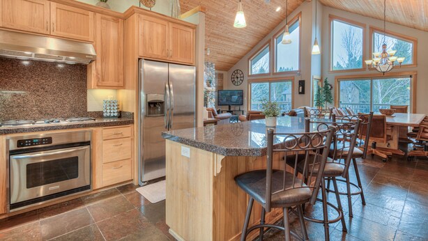 A spacious kitchen with granite countertops, stainless steel appliances, and a large island with bar stools. - Luxury Sunriver Vacation Rental, Hot Tub, A/C, SHARC (Sunriver)