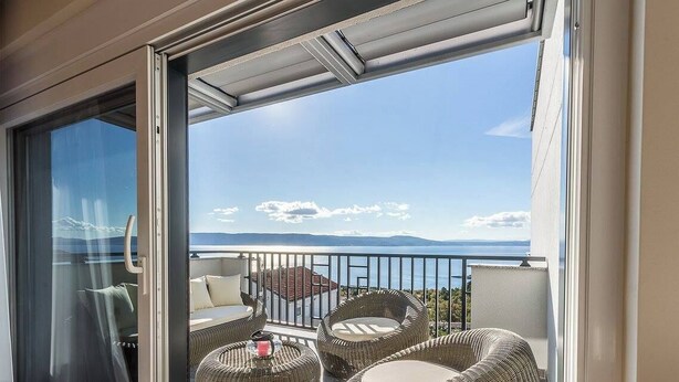 Een balkon met rieten meubilair en een glazen deur.