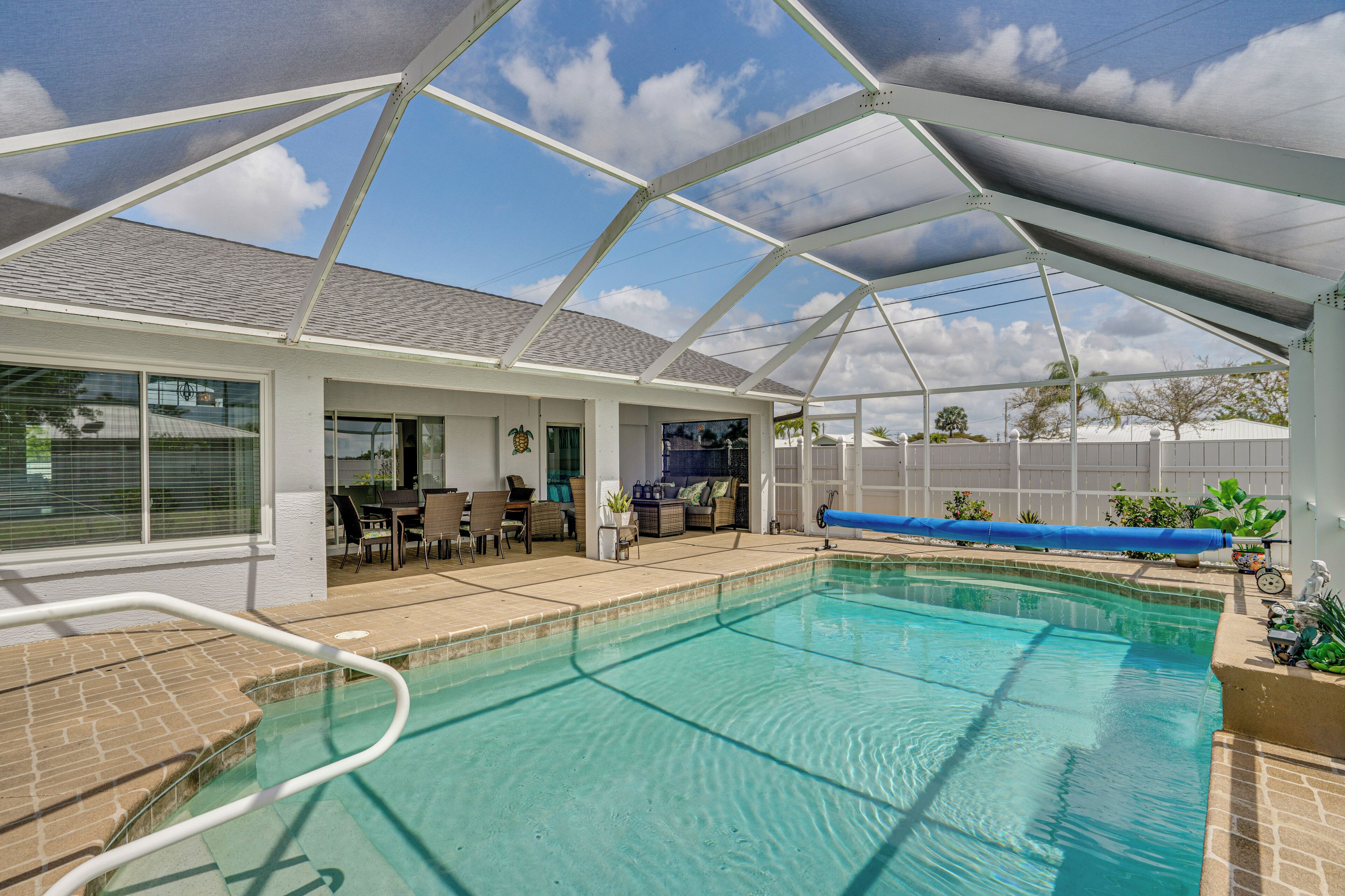 A covered swimming pool with a patio area, a covered seating area, and a view of the sky.