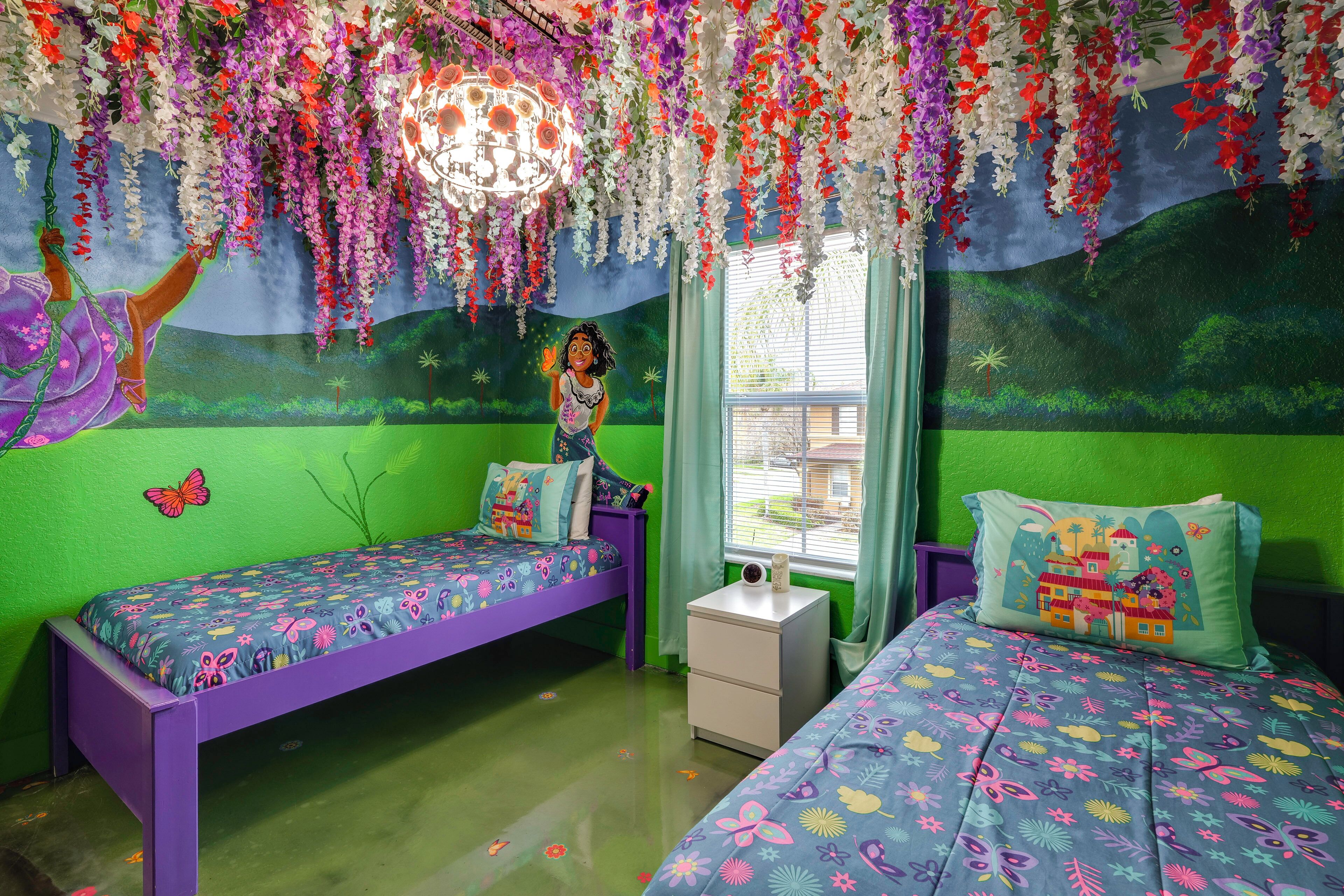 A room with two beds, a nightstand, a window with curtains, and a mural on the wall.