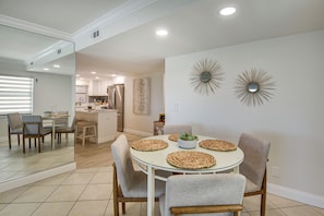 A dining area with a round table, chairs, and a kitchen in the background. - Sleek, Oceanfront Unit in Daytona Beach Shores! (Daytona Beach Shores)