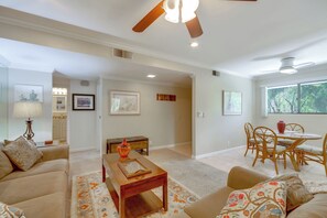 A living room with a sofa, coffee table, dining table, chairs, ceiling fan, and a view of the outdoors. - 5 Mi to Dtwn! Extended-stay Palm Springs Condo (Palm Springs)