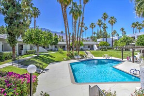 A swimming pool with a clear blue water, surrounded by palm trees and a well-maintained lawn. - 5 Mi to Dtwn! Extended-stay Palm Springs Condo (Palm Springs)