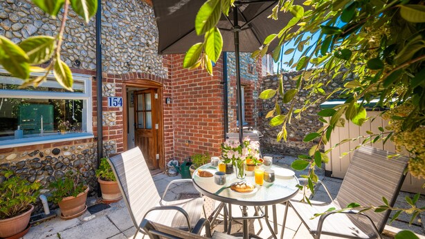Eine Terrasse mit einem runden Tisch, Stühlen und Topfpflanzen.