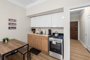 Une cuisine moderne avec des meubles blancs, une cuisinière en acier inoxydable et une table à manger en bois.