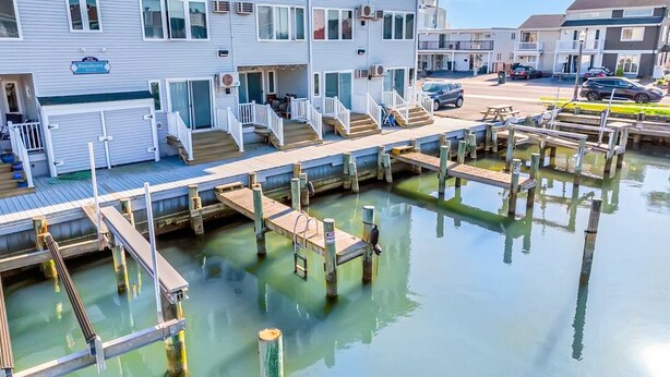Un hotel frente al agua con varias terrazas, un muelle y un estacionamiento.
