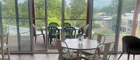 Ein geräumiger Balkon mit Tisch und Stühlen, große Fenster und Blick auf Grünflächen und Gebäude.