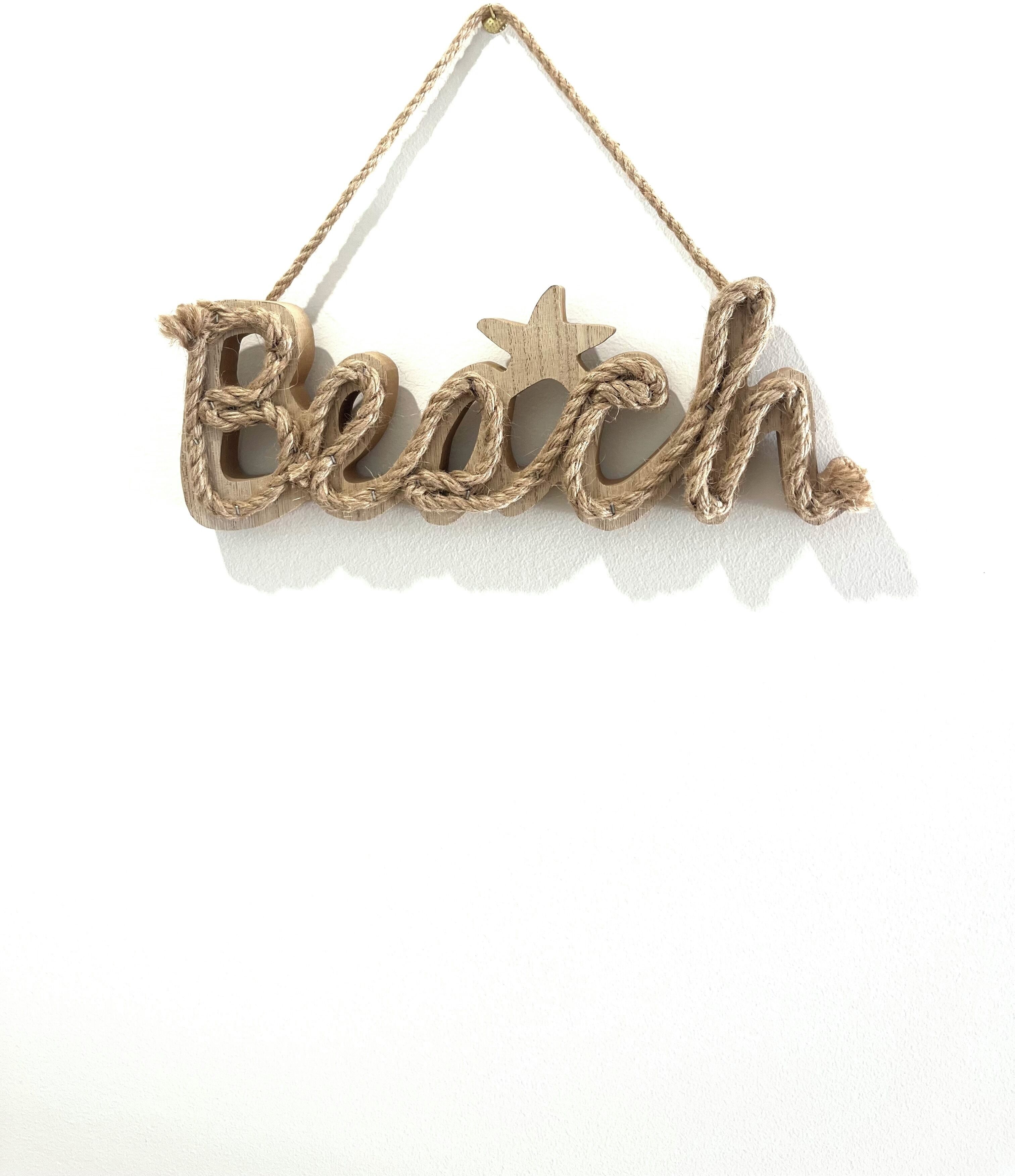 Una placa de madera con la palabra 'Beach' y una estrella, colgada de una cuerda.