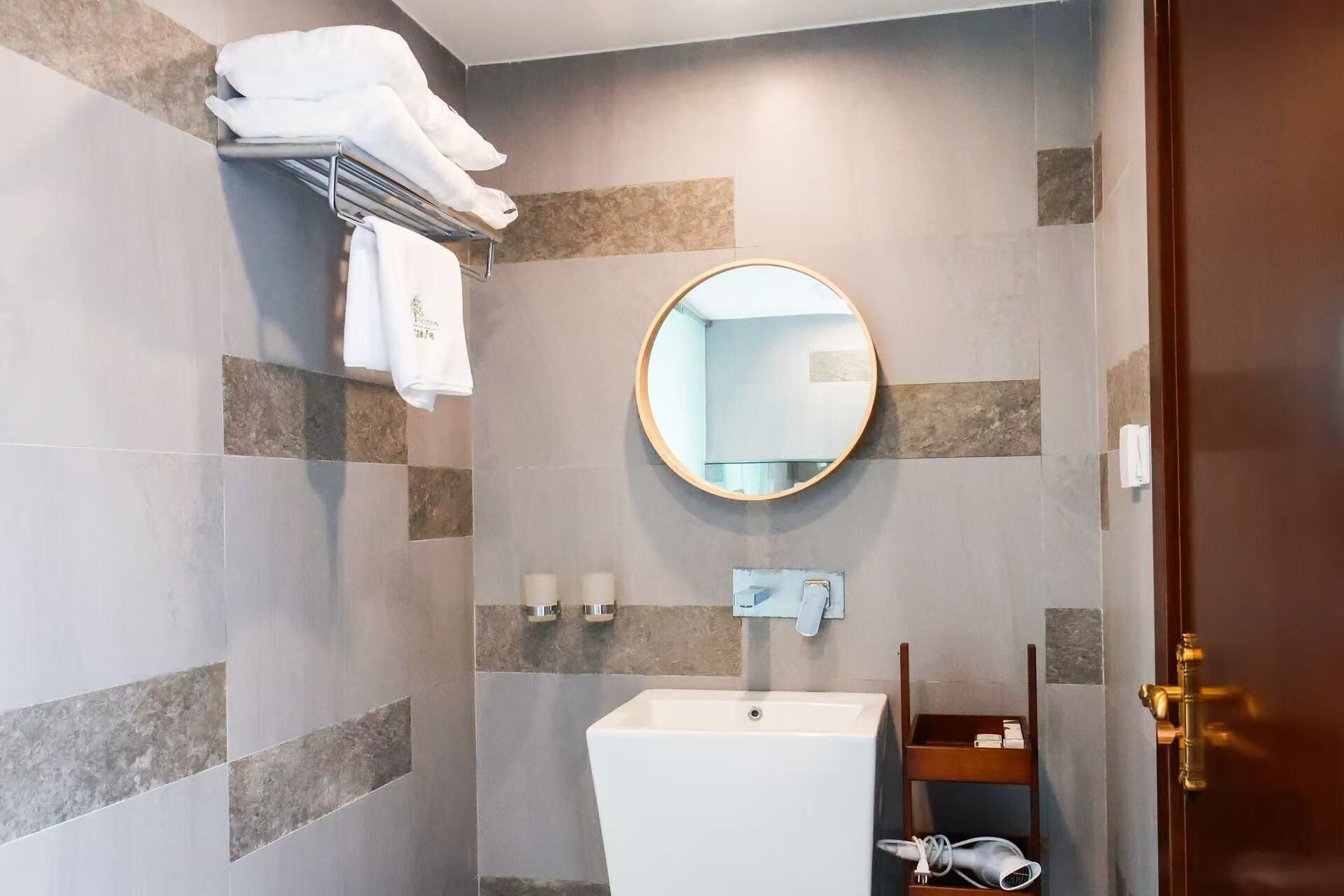 Une salle de bain équipée d’un lavabo, d’un miroir, d’un porte-serviettes et d’un distributeur de serviettes.
