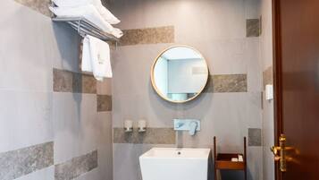 Une salle de bain équipée d’un lavabo, d’un miroir, d’un porte-serviettes et d’un distributeur de serviettes.