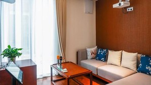 A modern living room with a sofa, a coffee table, a TV, and a projector mounted on the wall. - Book and Bed-Chong Ming (Shanghai)