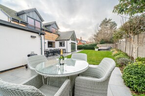 A patio with wicker furniture, a glass table, and a bottle of champagne. - Hungate Lodge, Old Hunstanton, Norfolk (Old Hunstanton)