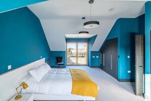 A modern bedroom with a bed, a desk, a chair, and a large window. - Hungate Lodge, Old Hunstanton, Norfolk (Old Hunstanton)