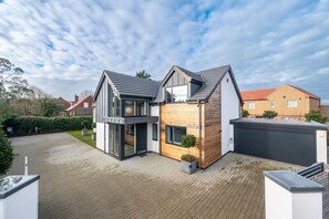 A modern two-story house with a garage, a driveway, and a well-maintained garden. - Hungate Lodge, Old Hunstanton, Norfolk (Old Hunstanton)