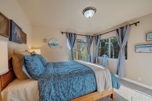 A bedroom with a bed, a wall clock, curtains, and a window with a view.