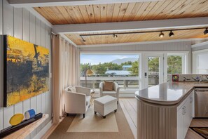 Et moderne køkken med en stor ø, et spiseområde med to stole og udsigt til et bjerg gennem store vinduer.