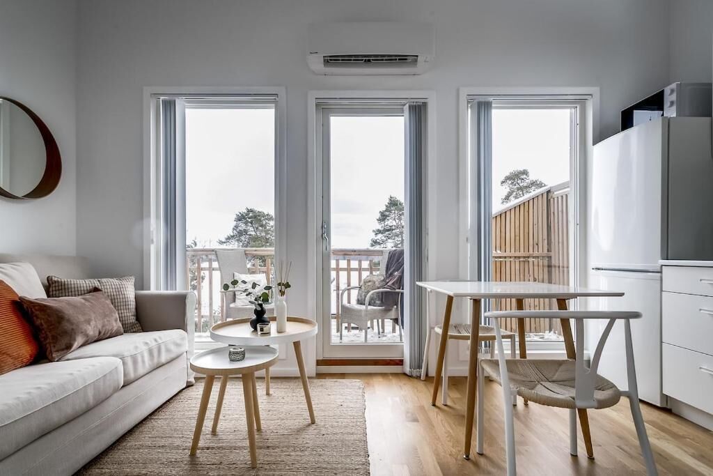 A modern living room with a sofa, a small round table, and a dining table with chairs.