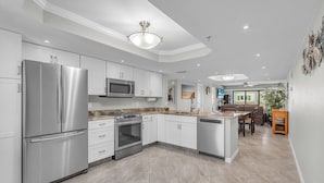 Una cocina moderna con electrodomésticos de acero inoxidable, armarios blancos y una isla central.