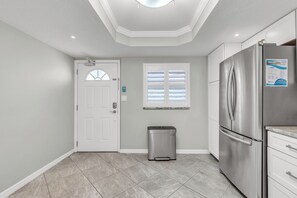 A kitchen with a stainless steel refrigerator, a trash can, and a window with blinds. - 🏖️Across the Street from Beach - Quick Walk!🐬Heated Pool🌴Madeira Place 201 (Madeira Beach)