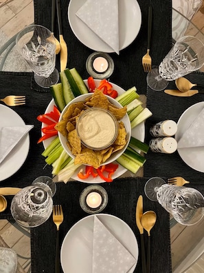 A dining table set with plates, cutlery, glasses, and a centerpiece of chips and vegetables. - 2-bed Garden Flat in Fulham (London)