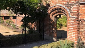 A brick building with an arched entrance, surrounded by greenery and trees. - 2-bed Garden Flat in Fulham (London)