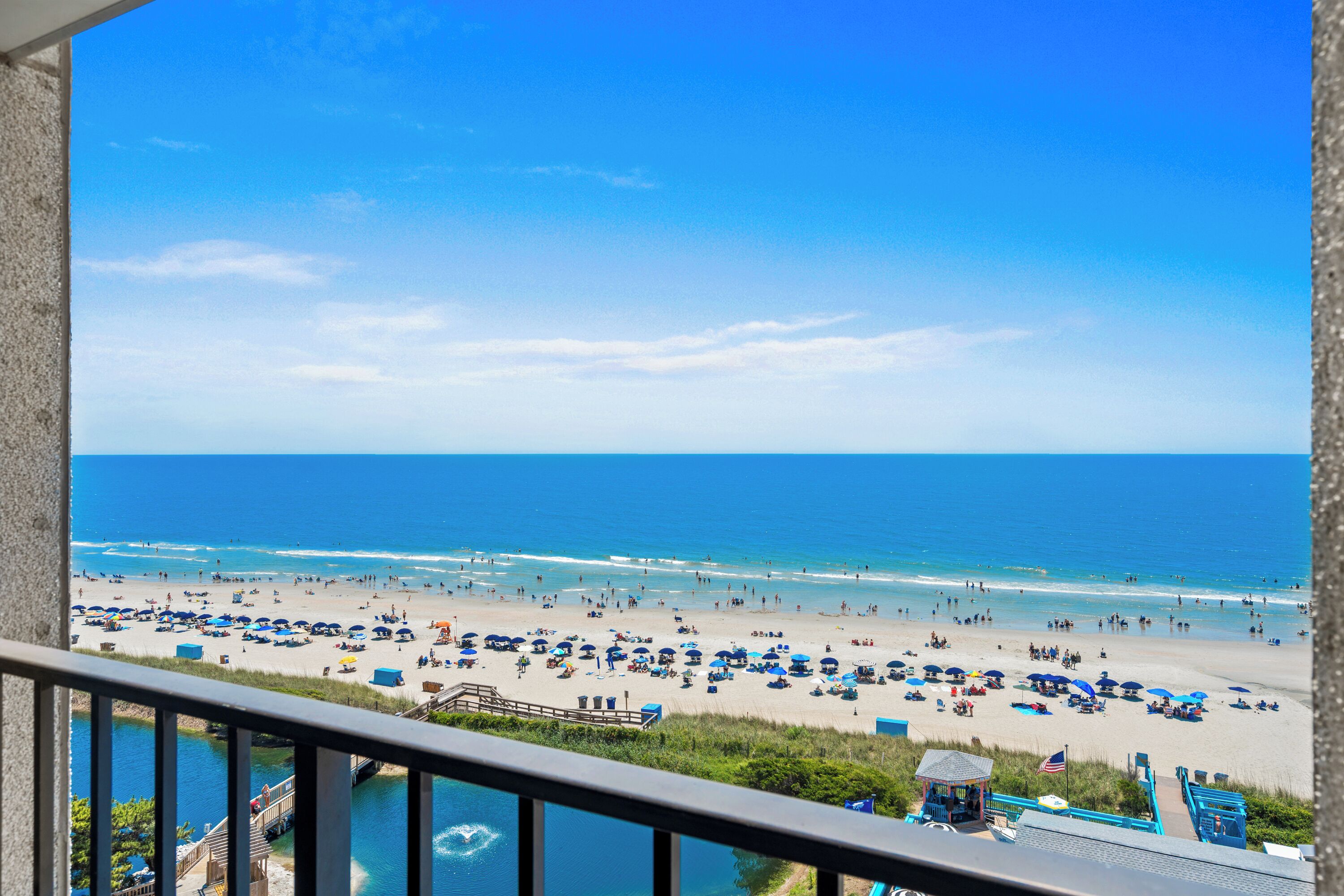 A beach with a clear view of the ocean, a wooden deck, and a gazebo.