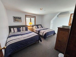 A bedroom with two beds, a nightstand, a lamp, a framed picture, and a wooden dresser. - Meadow Lane -Bar and Pool (Ogunquit)