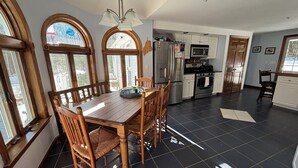 Une cuisine équipée d’une table à manger, de chaises, d’un réfrigérateur, d’un four à micro-ondes et d’un four traditionnel.