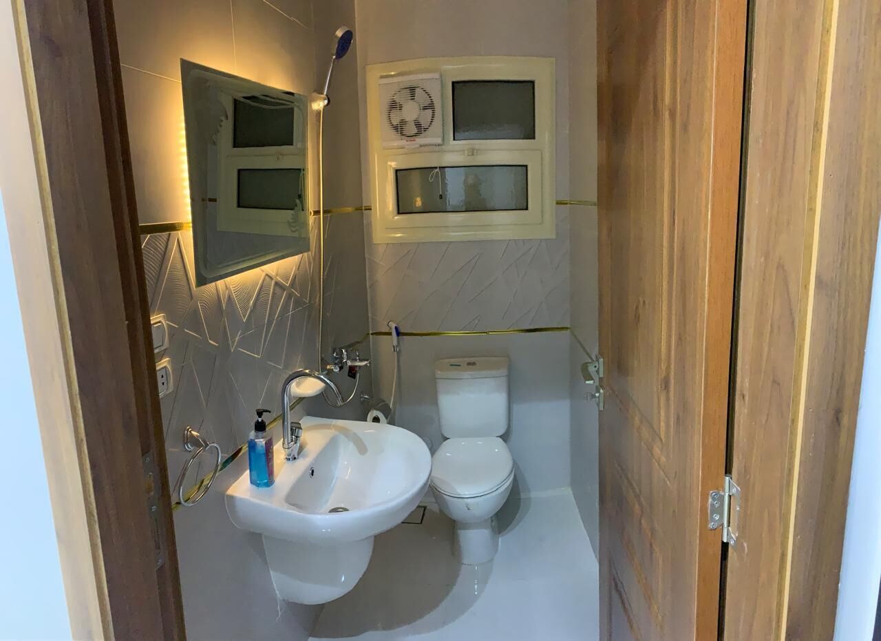 Un baño con lavamanos, inodoro y espejo.