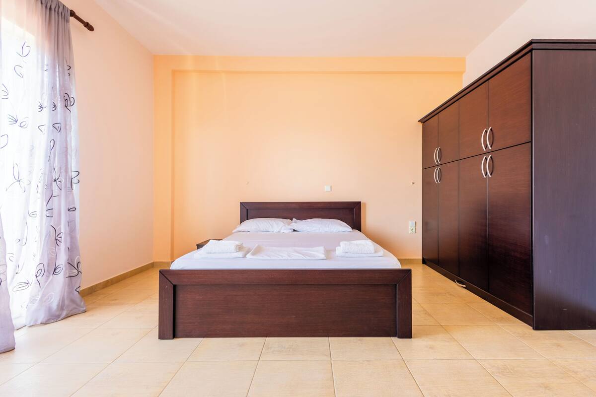 Une chambre à coucher avec un lit, une armoire et un rideau.