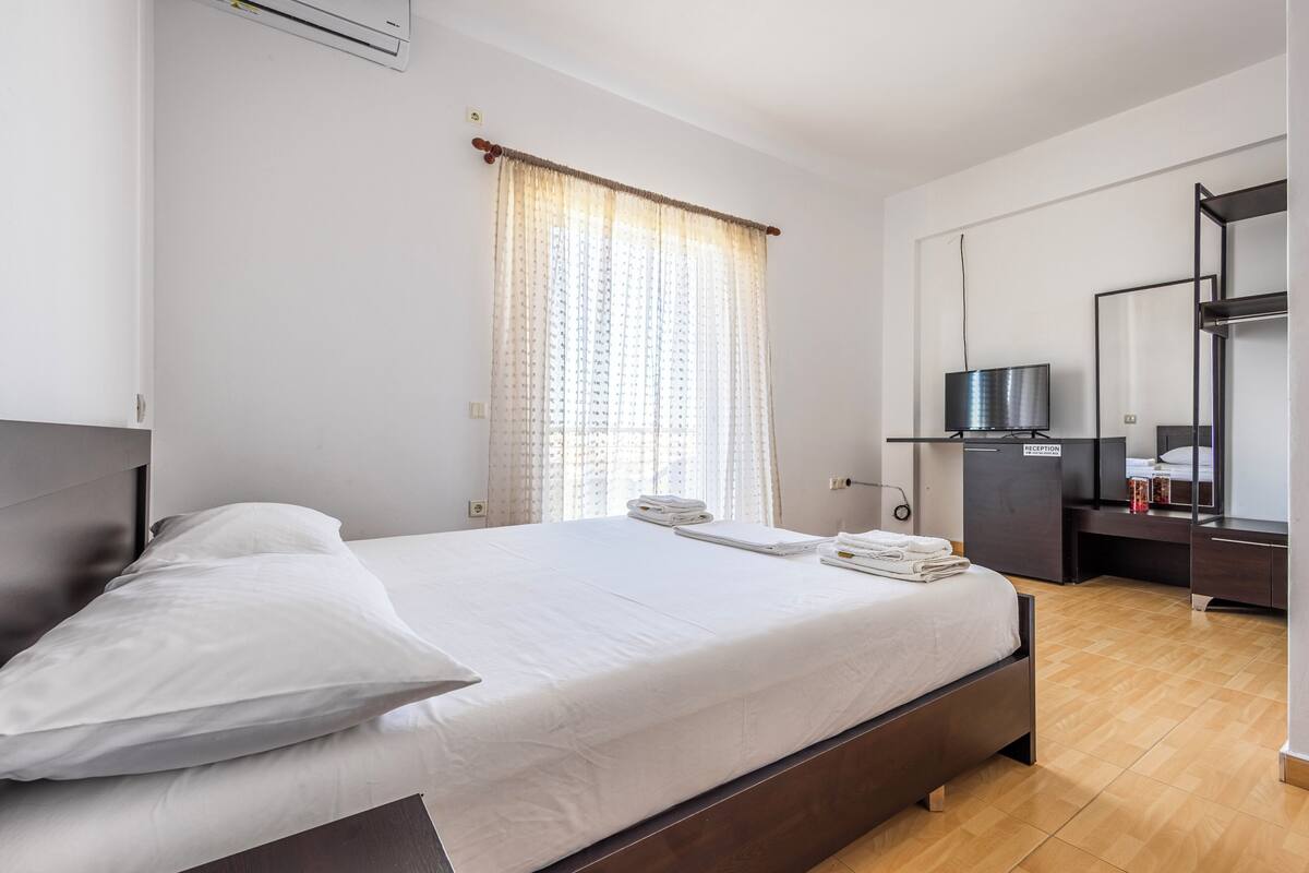 Une chambre d’hôtel équipée d’un lit, d’un bureau, d’une télévision et d’un miroir.