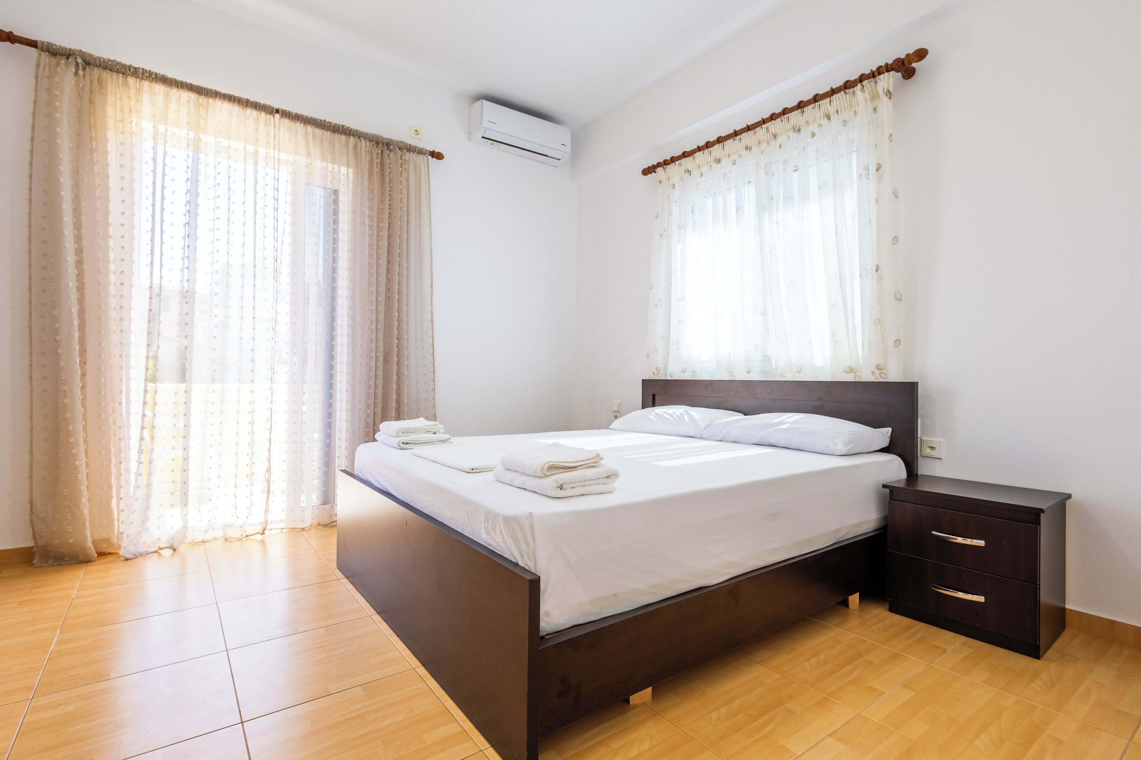 Un dormitorio con cama, mesita de noche y cortinas.