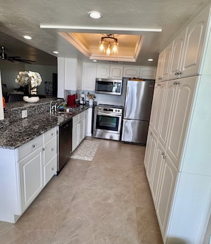 A modern kitchen with white cabinetry, stainless steel appliances, and a granite countertop.