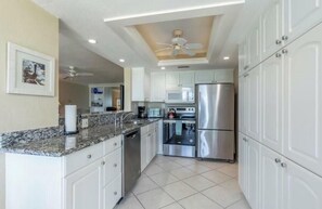 A modern kitchen with white cabinets, stainless steel appliances, and a granite countertop. - Condo on Naples Vanderbilt Beach close to the Ritz Carlton and LaPlaya Hotels. (Naples)