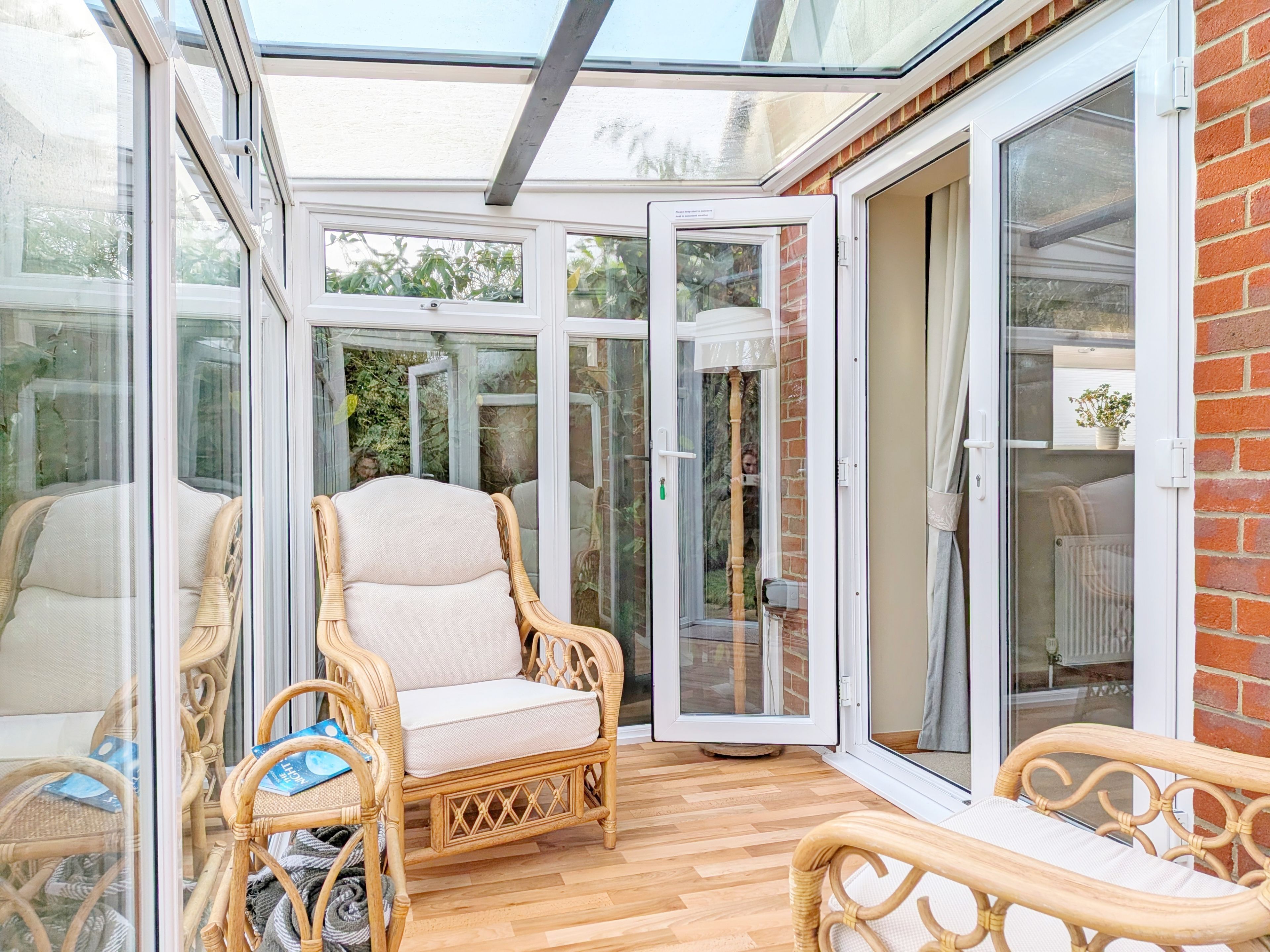 A conservatory with wicker furniture, a glass door, and a view of greenery.