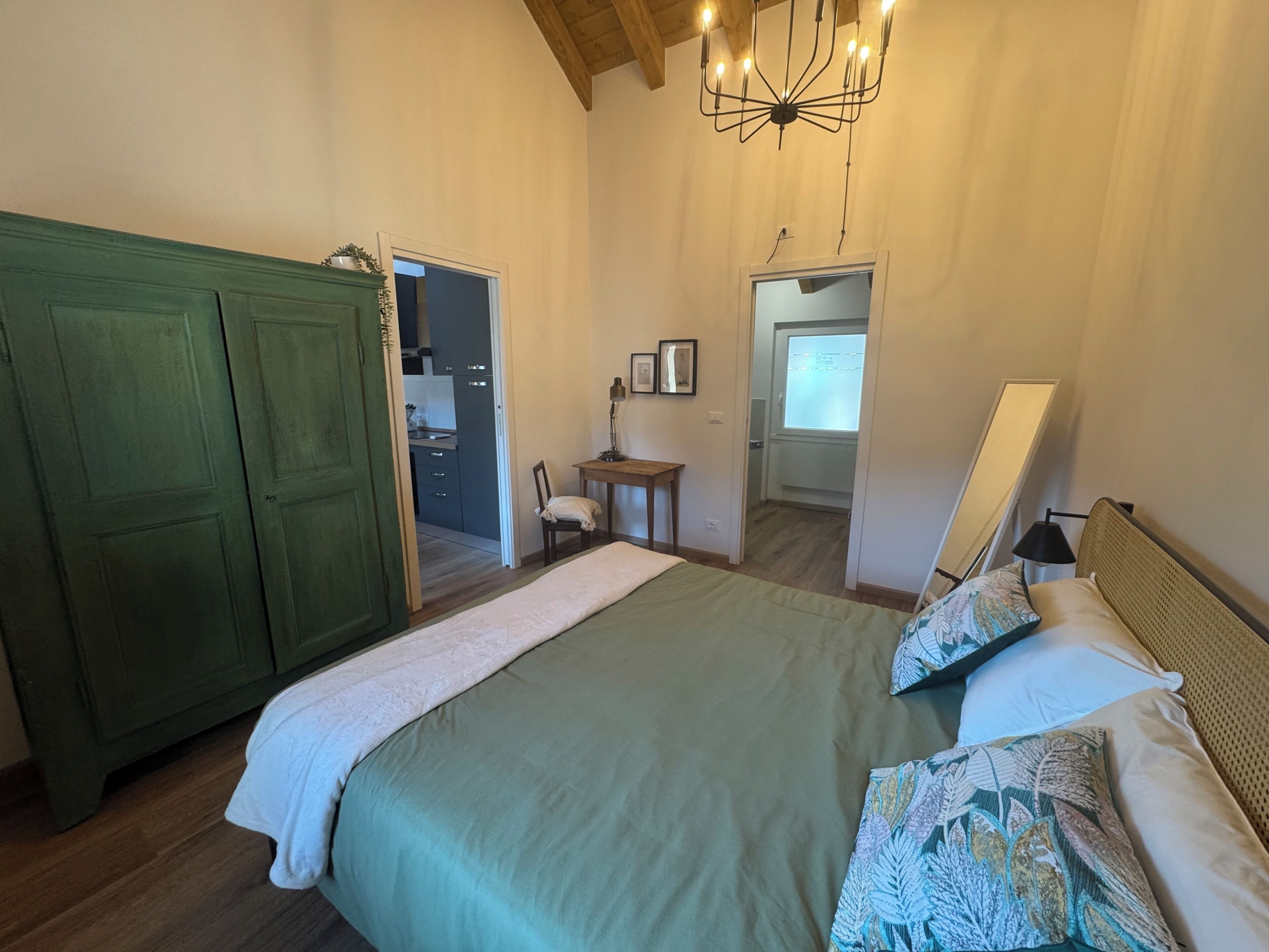 Un dormitorio con una cama, un armario verde, un escritorio y una silla.