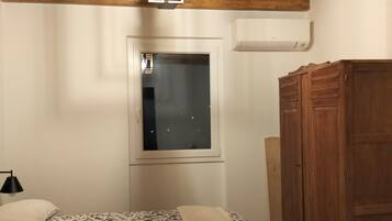 A bedroom with a wooden ceiling, a bed with floral bedding, a window, and a wardrobe.