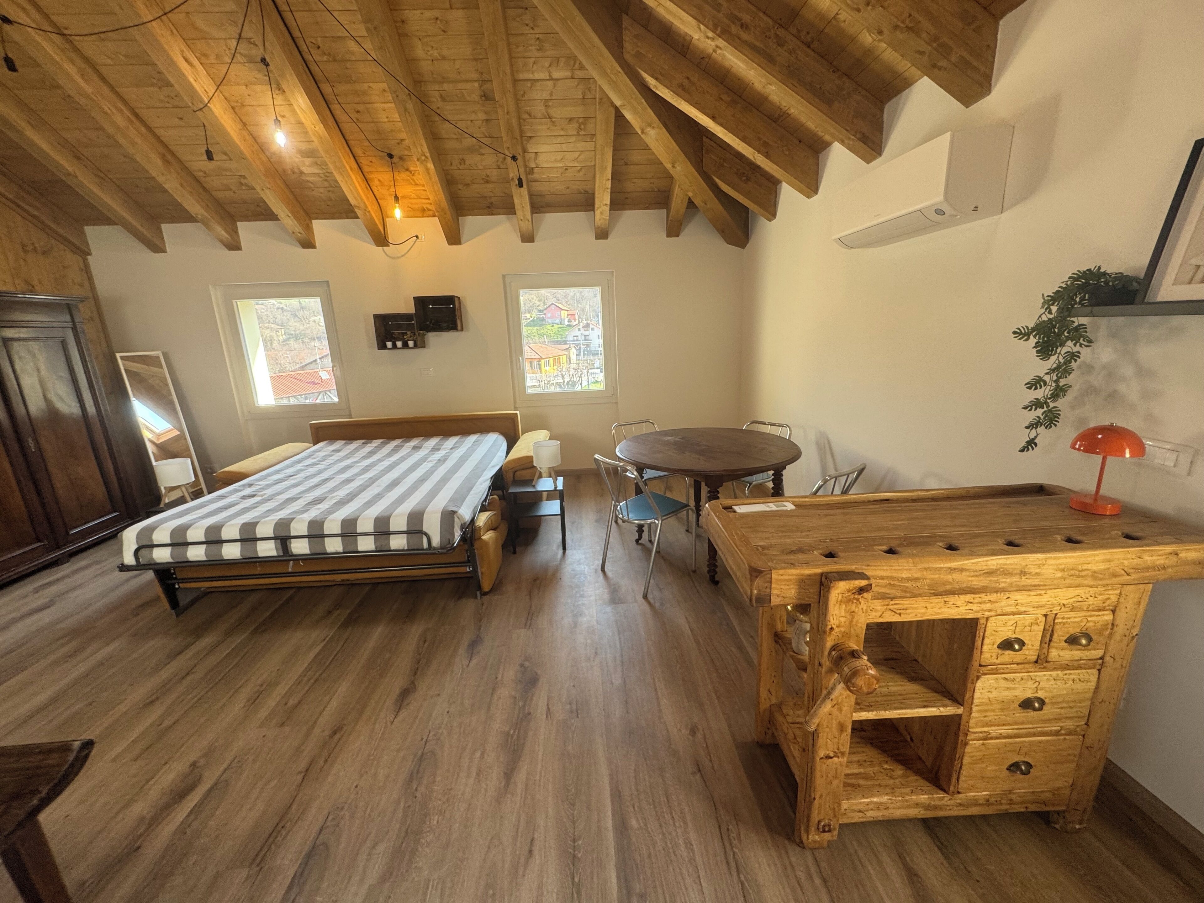 A bedroom with a bed, bedside table, chair, and a wooden desk with drawers.