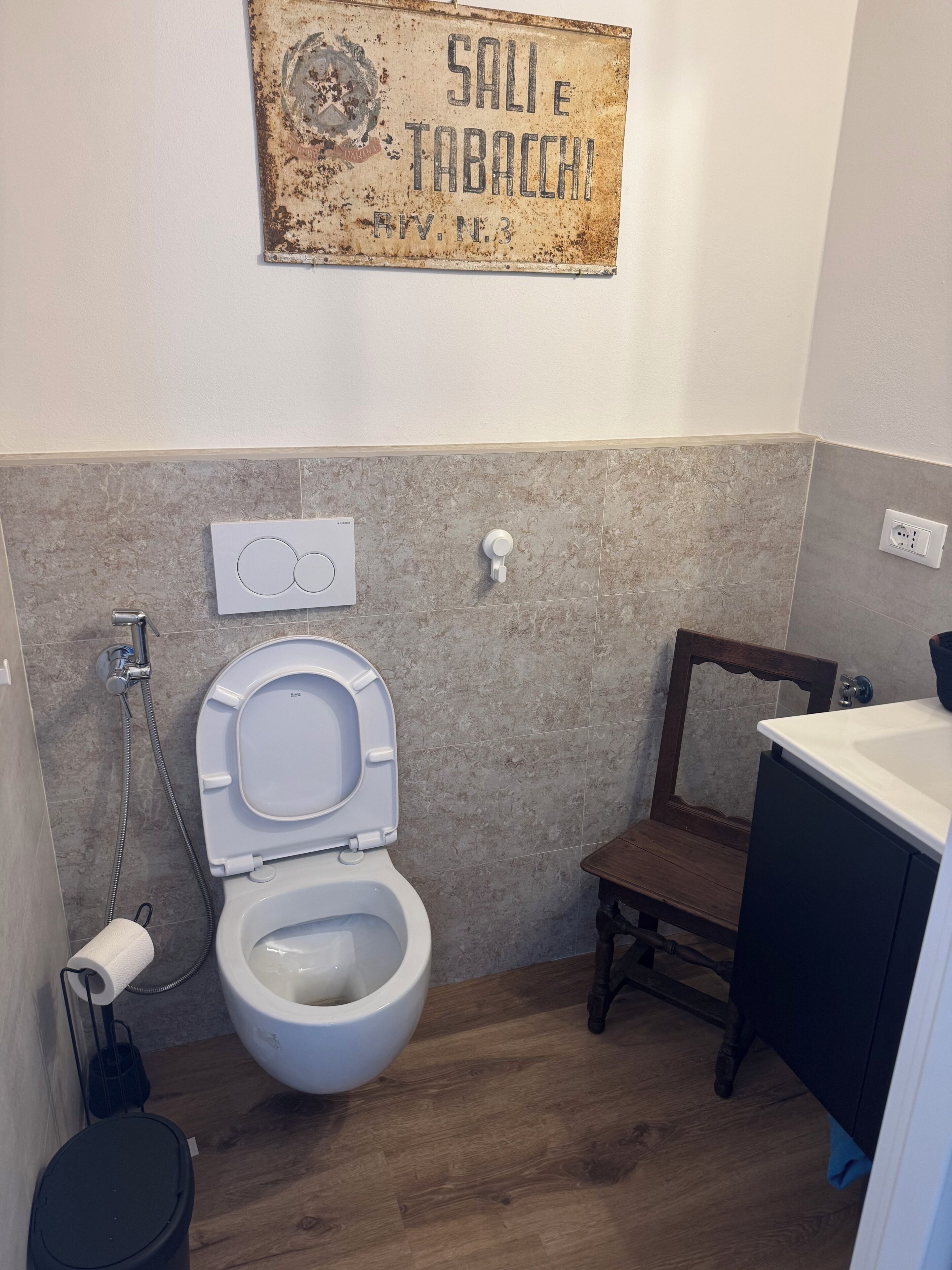 A bathroom with a toilet, a shower, a sink, and a wooden cabinet.