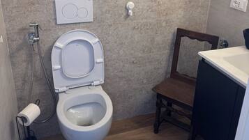 A bathroom with a toilet, a shower, a sink, and a wooden cabinet.