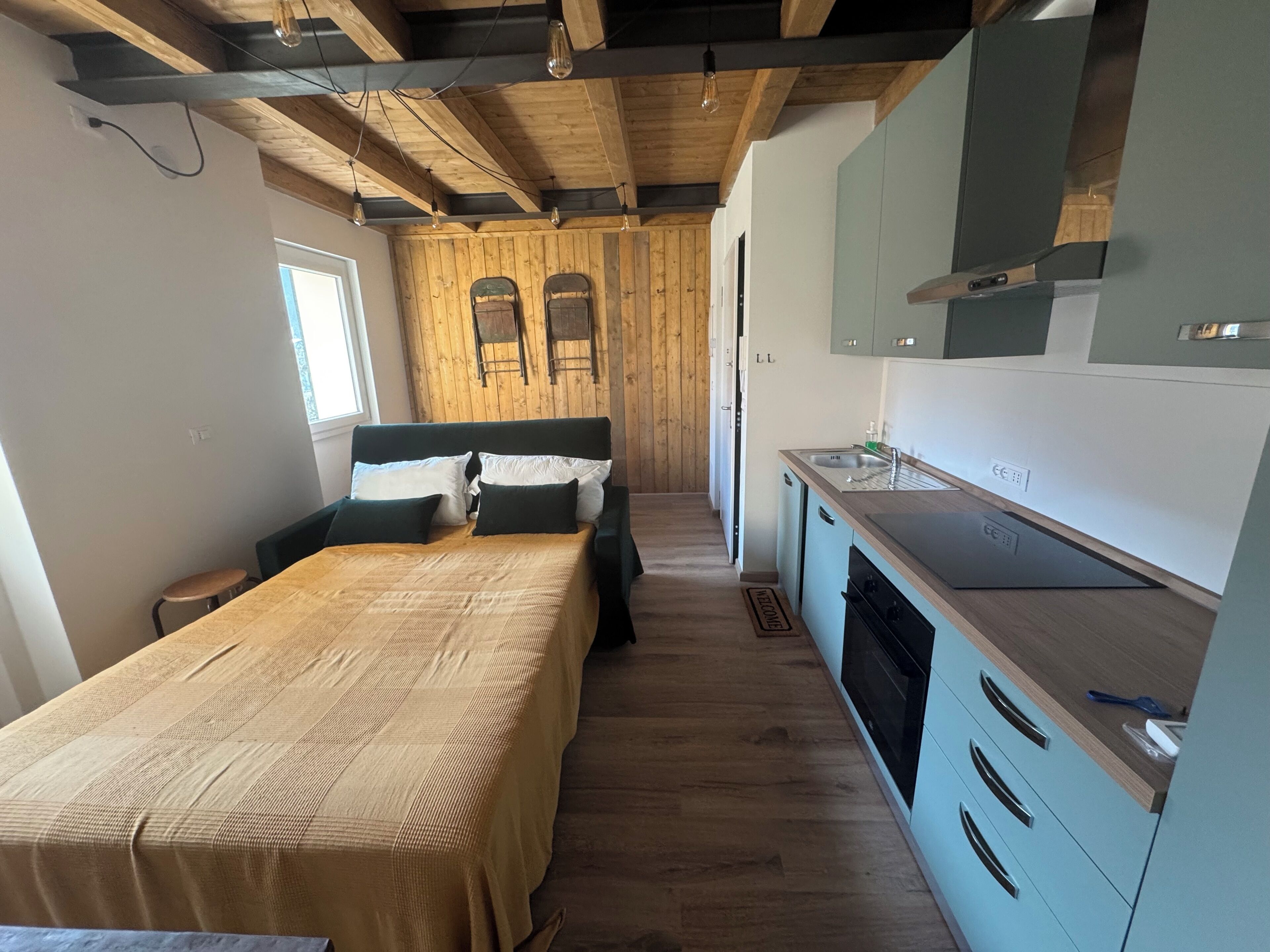 Una habitación pequeña con cama, kitchenette y pared de madera.