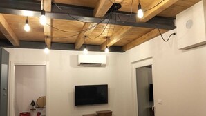 Un salón con televisión de pantalla plana, vigas de madera en el techo y un sofá azul.