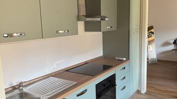 Eine moderne Küche mit hellblauen Schränken, einer Holz Arbeitsplatte, einer Edelstahl-Spüle und einem schwarzen Backofen.