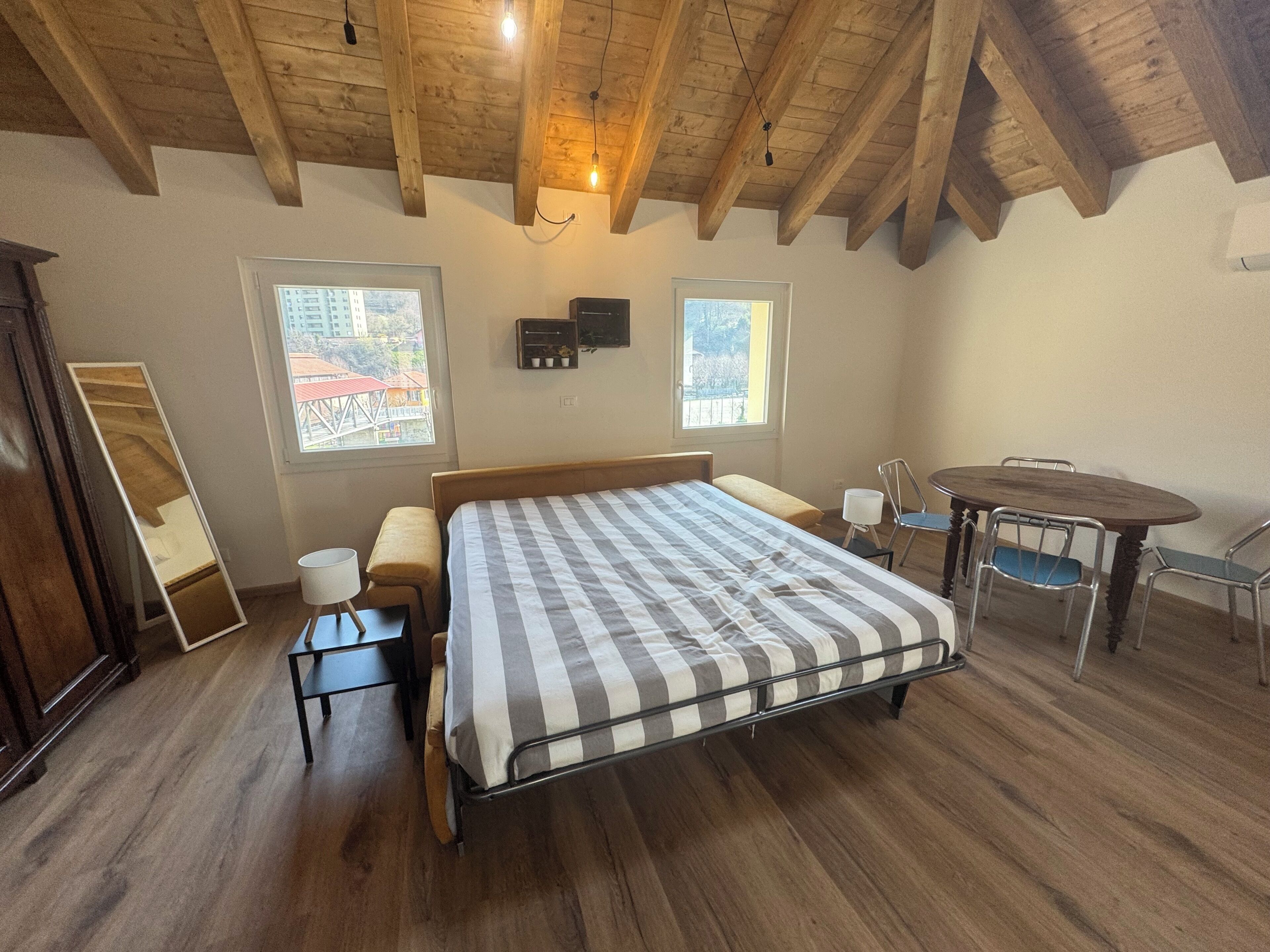 A bedroom with a bed, bedside tables, a chair, a small table, and a window.